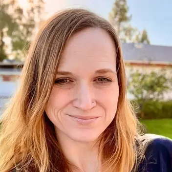 Meg Kennedy, smiling, outdoors at golden hour